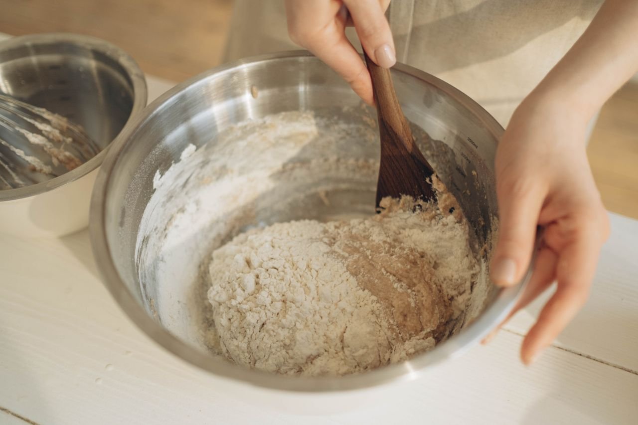 The Art of Drawing Readers In: Your attractive post title goes here Hands mixing dough with a wooden spatula in a stainless steel bowl, perfect for baking themes.